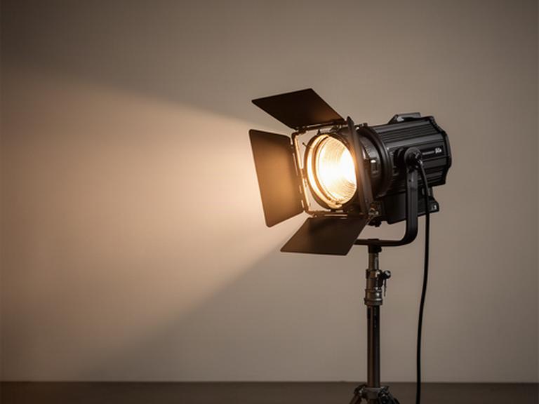 Fresnel-lamp met barn doors gericht op een decorwand tijdens een locatieproductie